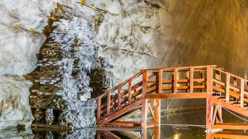 Slanic Prahova Mine - a wooden pedestrian bridge leading to a small tunnel surrounded by beautiful salt structures.